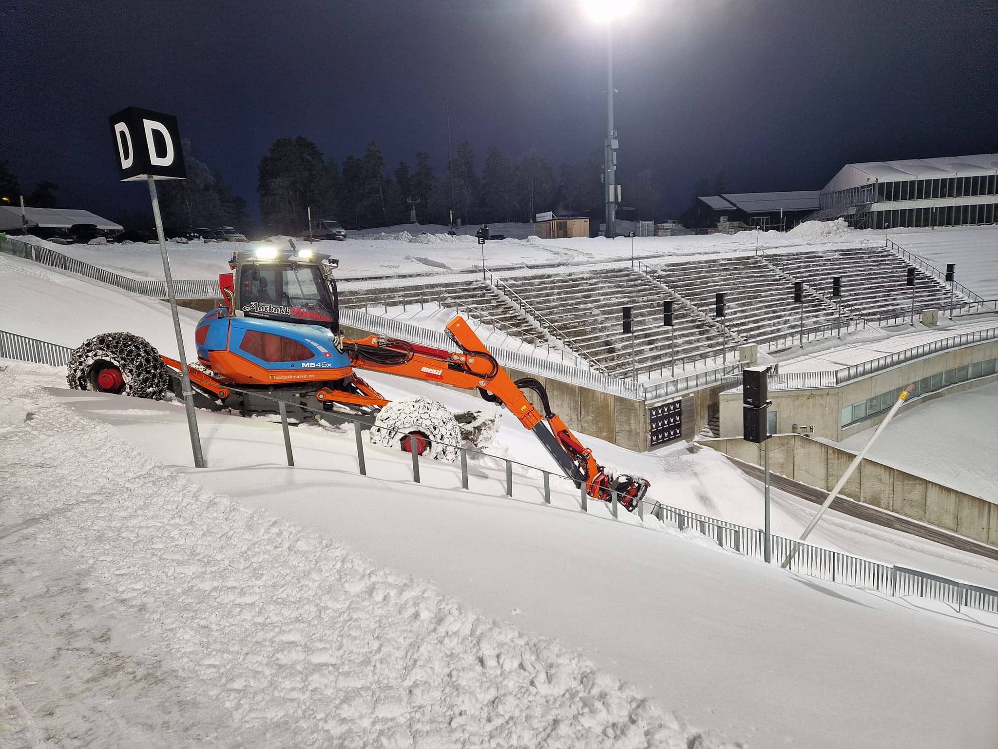 Menzi Muck maskin i arbeid med snø på stadium