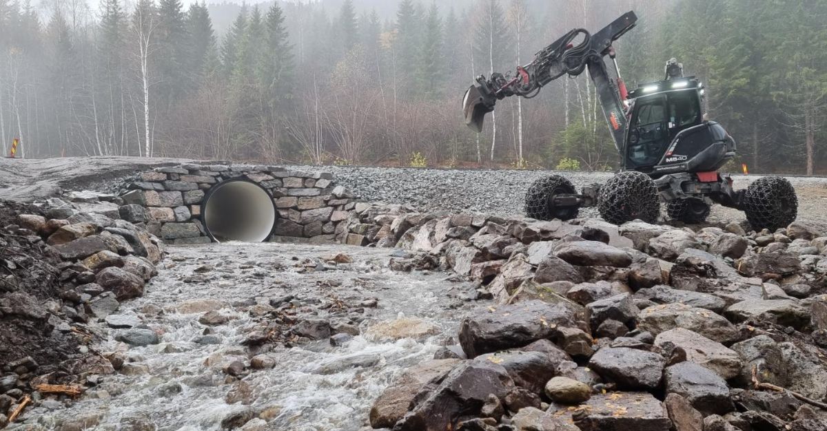 Menzi muck maskinen ved natursteinsmur rundt kulvert for elv gjennom vei