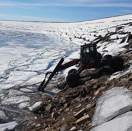 Menzi Muck maskin i arbeid ved islagt vann