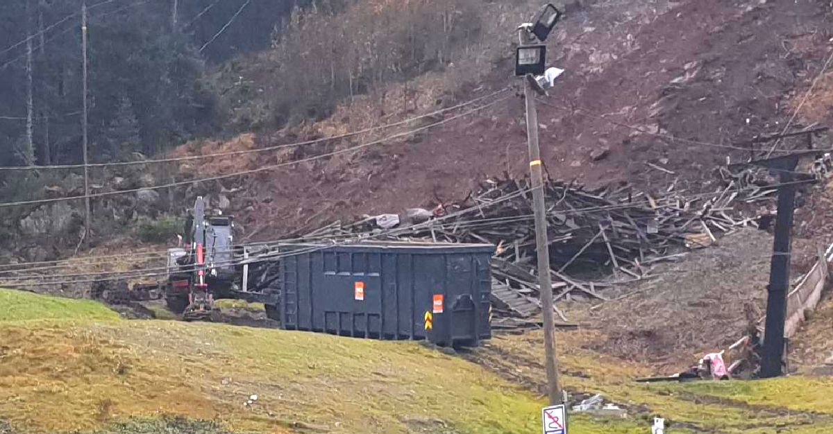 Menzi muck maskinen på tomt med plankehaug